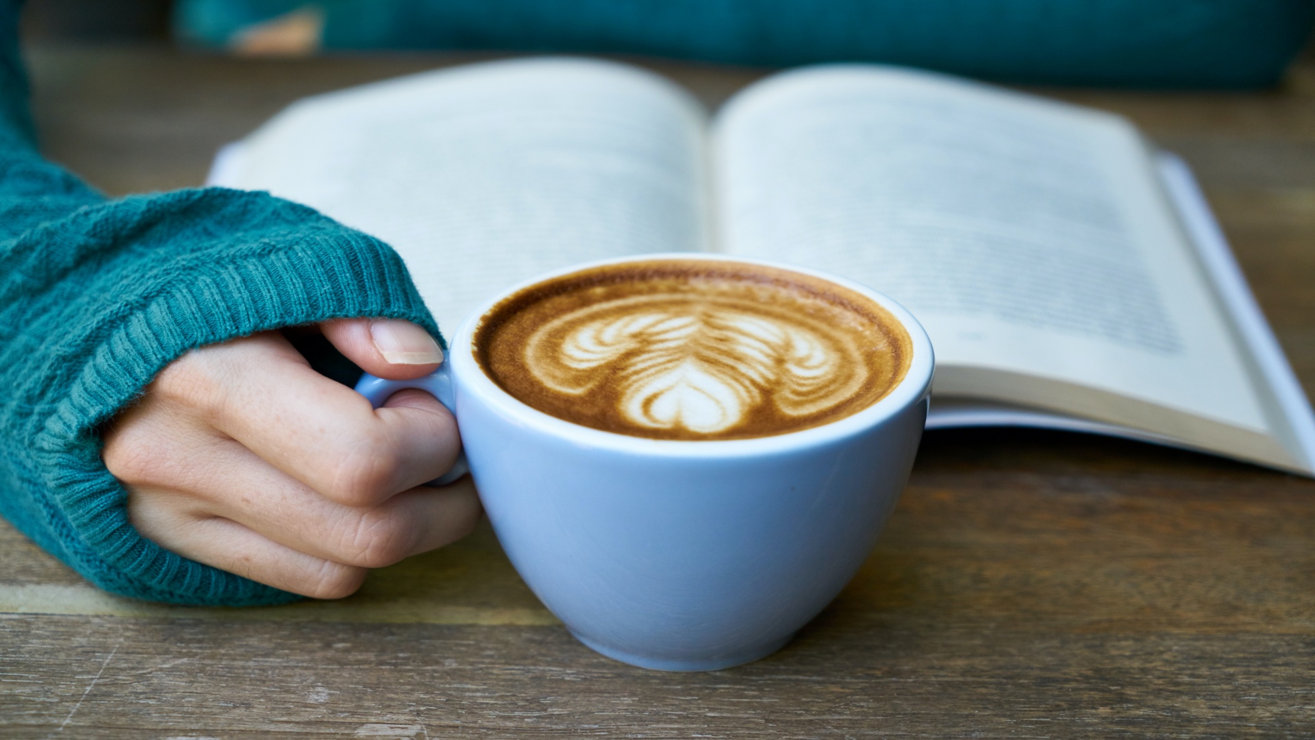 a girl holding a cup of coffee while she is reading